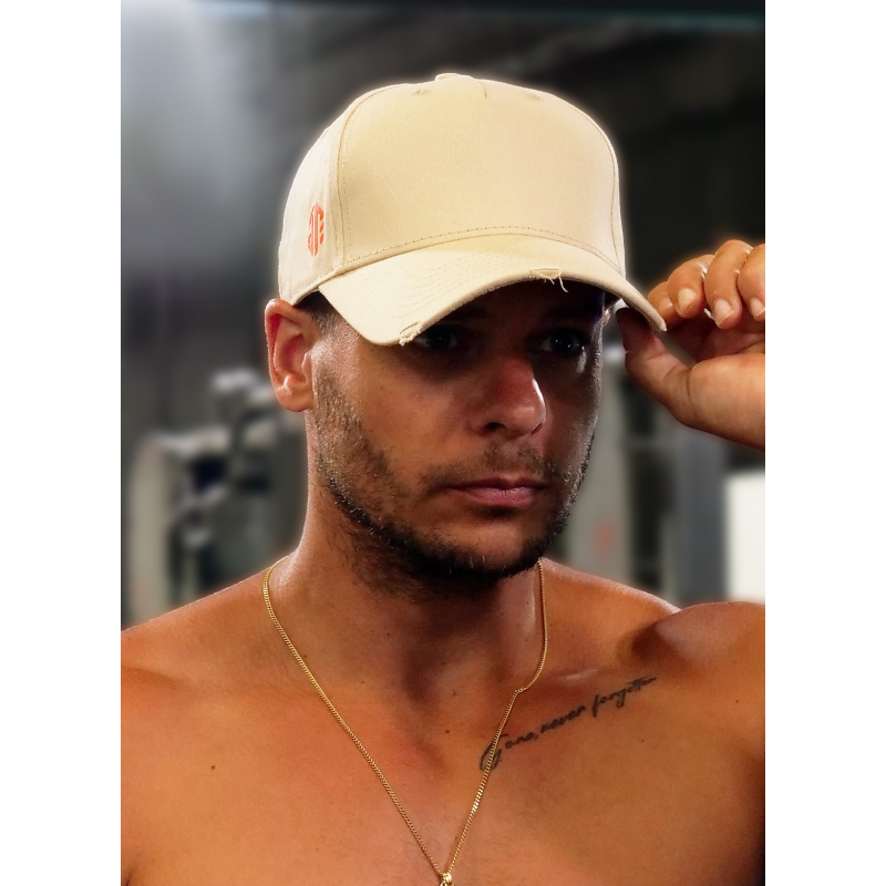 Casquette créme en coton avec attache orange portée par un homme nu-torse, lisant légèrement la visière.