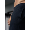 Homme sportif portant un pantalon de jogging noir, vue rapprochée sur la taille et une couture, logo discret sur le tissu noir.